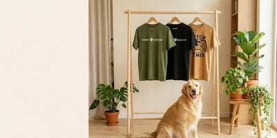 Animal Obsessed dog tees hanging on a wooden rack beside a golden retriever
